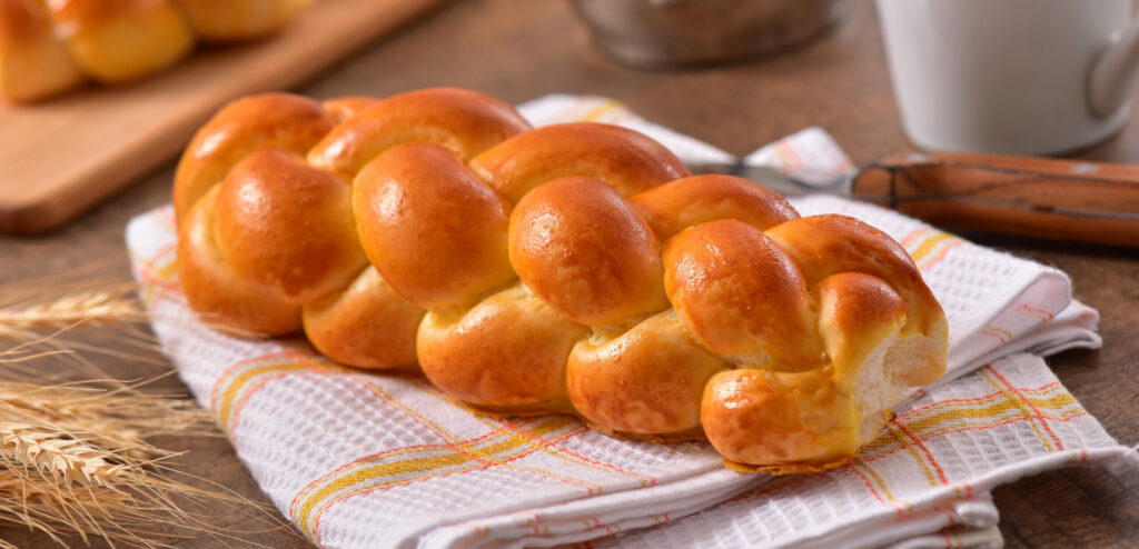 Challah bread resting on a cloth on top of a table made from the best challah bread recipe