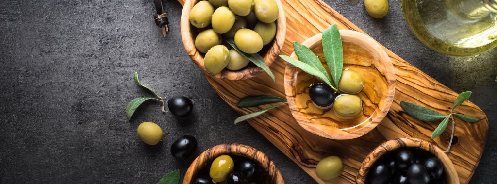 Bowls of olives on a wooden board as a great snack.