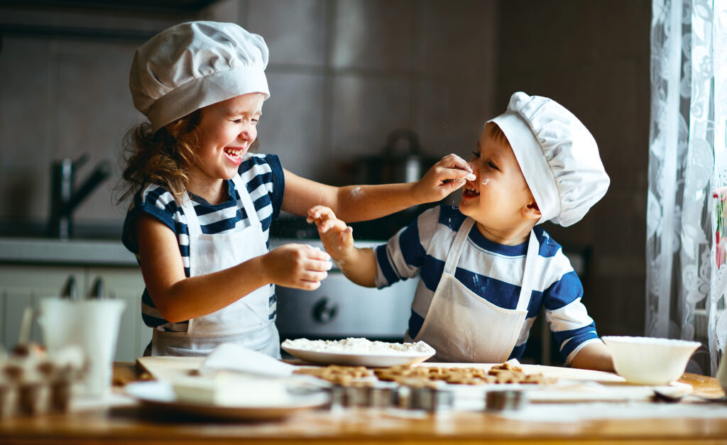 Kids happily cooking together making a delicious healthy recipe using olive oil