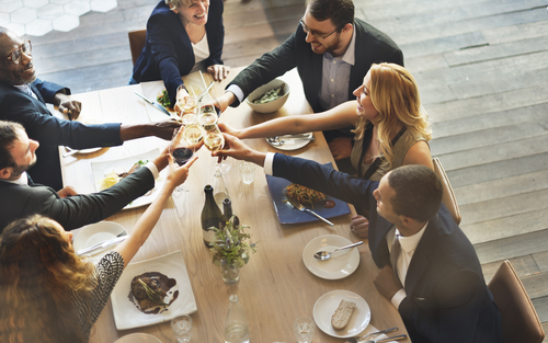 Adults toasting at dinner table