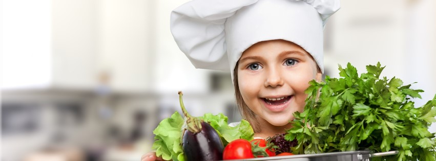 Young girl in chefs hat with vegetables