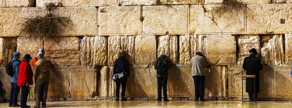 A row of people bowing their heads in prayer at the Western Wall in Jerusalem.