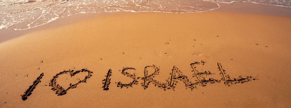 The phrase I love Israel written on beach sand at sunset., symbolizing the joy of the Lord is our strength.