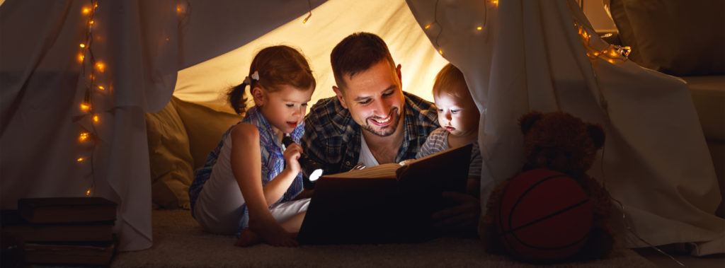 A father reading to his young children in a makeshift fort, which is one of many practical ways to leave a legacy.