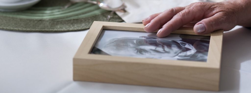 Woman touching photo of late husband and reminiscing.