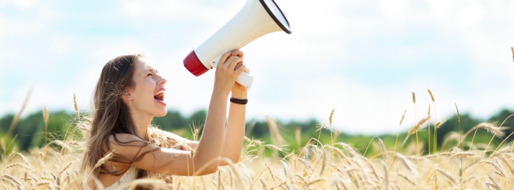 Woman with megaphone in wheat field, speaking life to the harvest.