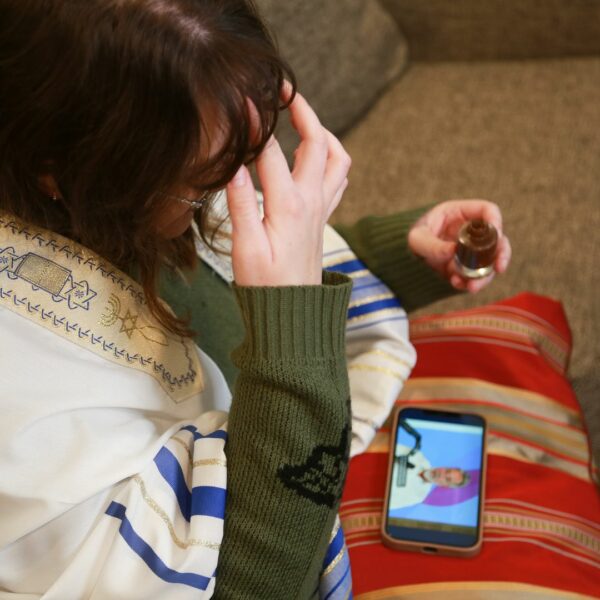 xA woman at home watching a video of Rabbi Curt Landry teaching how to use the The King’s Oil.