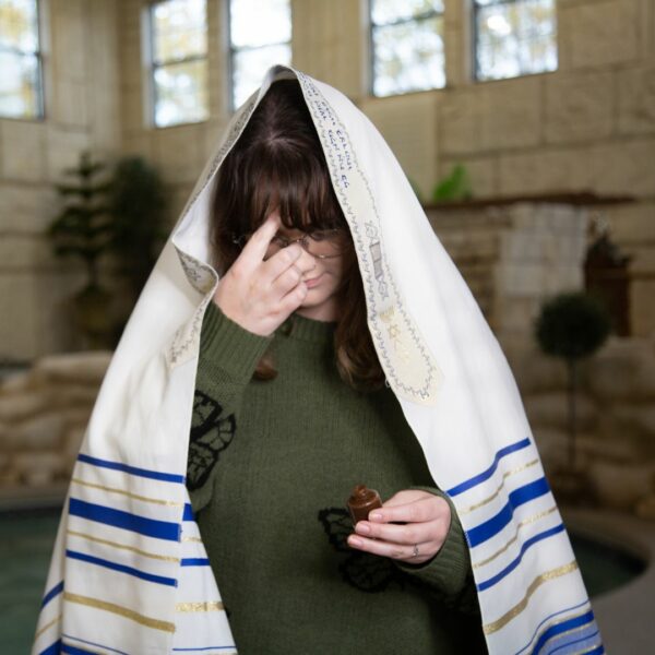 A woman wearing a tallit annointing her forhead with The King's Oil.